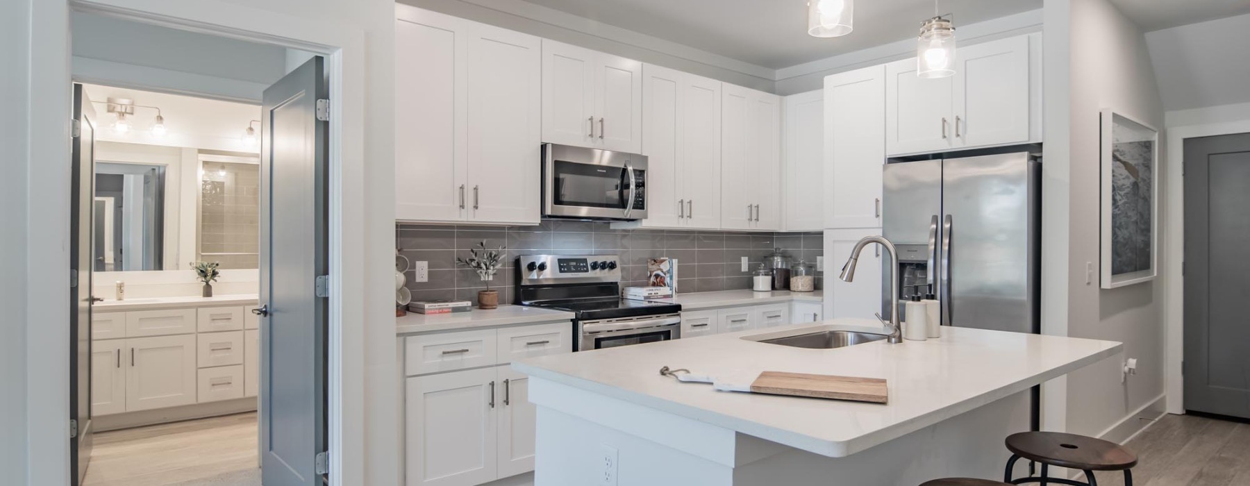 Spacious and well lit kitchen with wood floors and stainless steel appliances. 