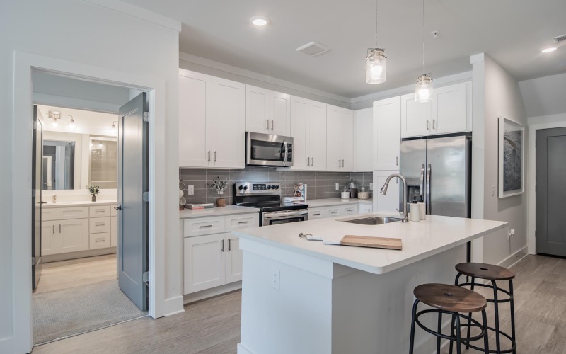 Spacious and well lit kitchen with wood floors and stainless steel appliances. 